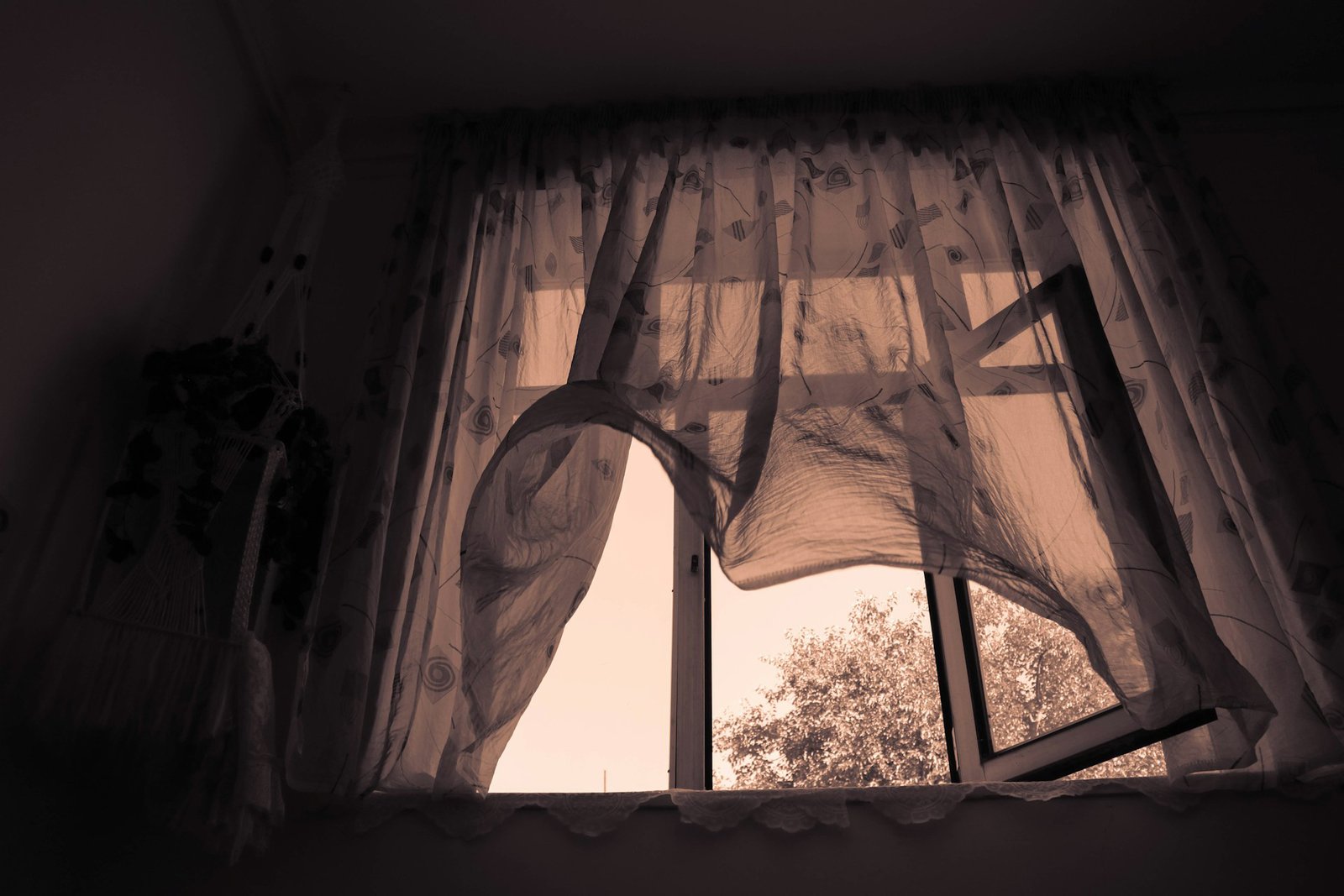 Fensterrahmen mit Vorhang der sich durch Luftbewegung leicht bewegt